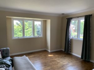 The empty living area of a home with wood floors and new windows
